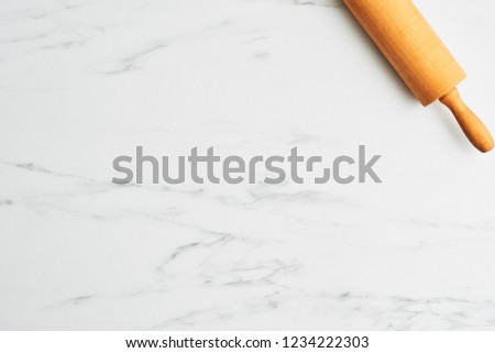 Simple baking background with rolling pin on white marble table. Top view, copy space for text.