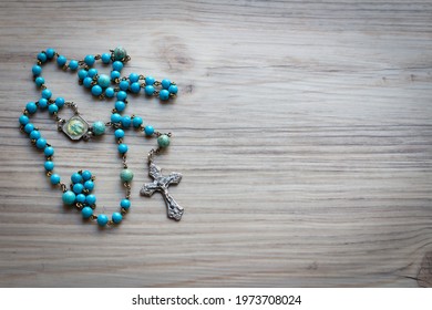 Simple blue rosary on wood background with copy space