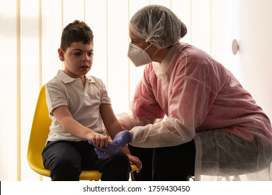 simple and cheated chair, a woman nurse or physiotherapist in a protective gown, protective mask, latex gloves, attends to and speaks during the coronavirus of her patients, a child disabilities - Shutterstock ID 1759430450