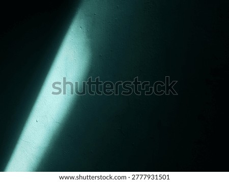 Simple clean design with a diagonal beam of sunlight on a textured teal wall.