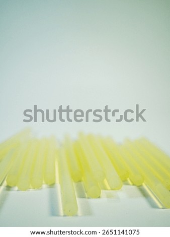 A simple, clean studio shot highlighting yellow hot glue sticks, ideal for crafts, DIY projects, home repairs, and demonstrating adhesive materials.