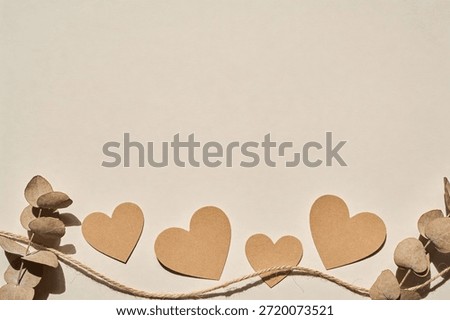 A simple composition featuring natural elements like dried eucalyptus and craft paper hearts with twine