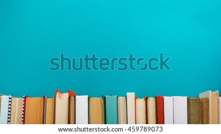 Simple composition of hardback books, raw of books on wooden deck table and blue background. Books stacking with no labels, blank spine Back to school Copy Space Education background Office supplies 