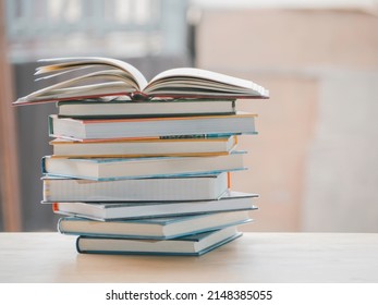 A simple composition of many books, stack or pile of books on wooden table, one of them open with copy space.