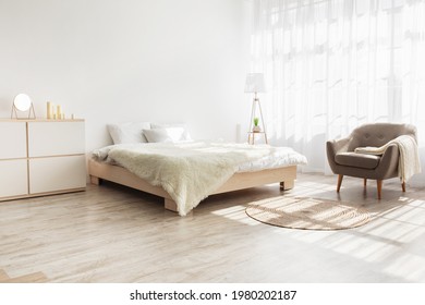 Simple design, ad, offer and modern home style. Double bed with pillows, soft blanket, carpet, lamp, armchair and furniture, on wooden floor. White wall, big window with curtains in bedroom interior - Shutterstock ID 1980202187