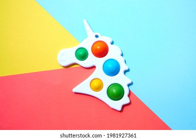 Simple dimple in form unicorn on colorful yellow, red and blue background.