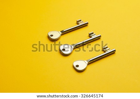 Simple door keys organized in a row over bright yellow background