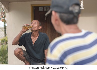 A Simple And Easygoing Man Talks To A Neighbor While Drinking A Cold Bottle Of Beer By The Veranda. Older Men Relaxing And Being Carefree.