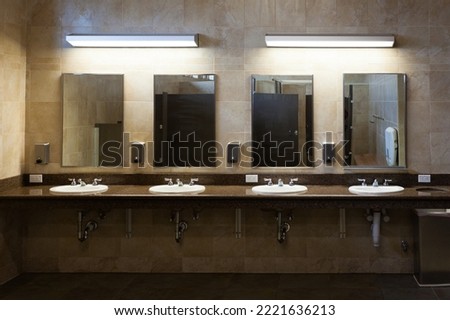 Simple efficiency of clean tiled modern interior public washroom with multiple sinks, faucets, soap dispensers and mirrors