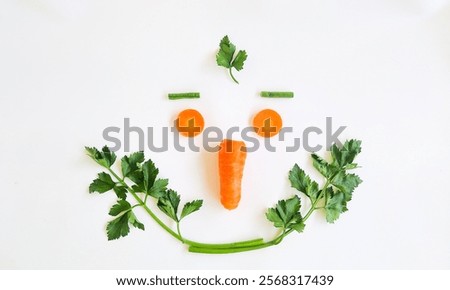 A simple face design made with vegetables: two carrot slices as eyes, a whole carrot as the nose, and parsley leaves forming a smiling mouth on a white background.
