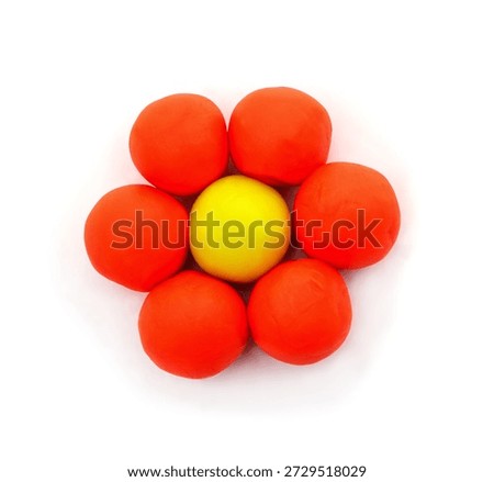 A simple flower shape created from round orange clay petals and a yellow center isolated on a white background.