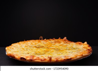 Simple four cheese delivered pizza with crunchy crest and golden yellow orange tint studio low key still life against a dark background