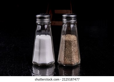 Simple Glass American Diner Style Salt And Pepper Shakers On A Black Table With Reflections