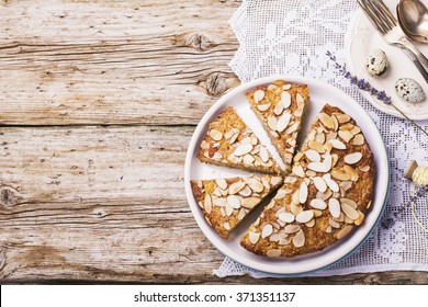 Simple homemade pecan pie decorated with petals of almond with a wooden background Serving Easter used blue and yellow colors, quail eggs, lavender flowers, vintage linen tablecloth handmade.