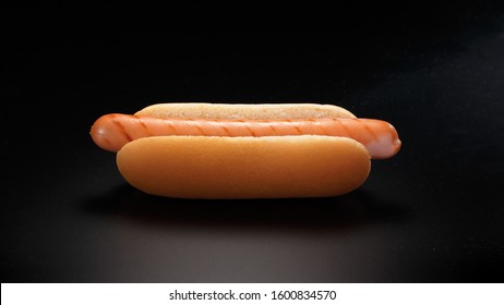 Simple Hot Dog (sausage With A Bun) On A Black Background.