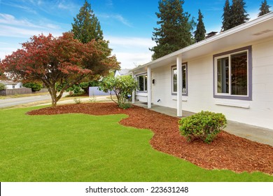 Simple House Exterior In White Color. Front Yard Landscape With Sawdust And Lawn.