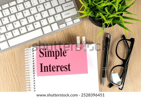 Simple interest concept with notebook, keyboard, and eyeglasses on a wooden desk . 