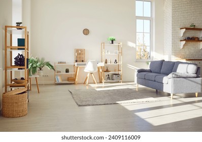 Simple interior design of a new clean modern apartment. No one at home, in a cozy bright sunny living room with white walls, gray sofa, wooden shelves, green plants, warm rug and laminate flooring  - Powered by Shutterstock