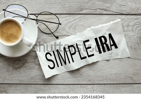 SIMPLE IRA (Savings Incentive Match Plan for Employees) concept.Piece of torn paper with SIMPLE IRA text on wooden table