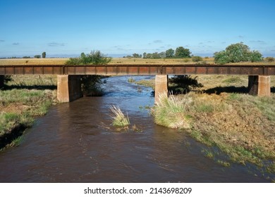 Simple Iron Bridge For Crossing Train Tracks Crossing A River With Vegetation In Rural Landscape