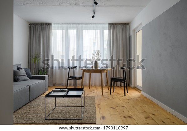 Simple living room with exposed, bare\
concrete on wall and ceiling and pine wood\
floor