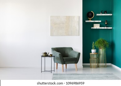 Simple living room interior with green armchair, plants, teapot set on the table and marble shelves on the wall - Shutterstock ID 1096986959