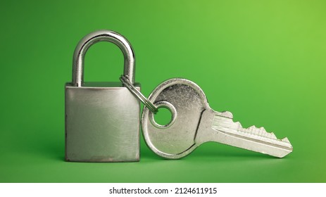 Simple lock and key. Small worn padlock with over large shiny key. Business data encryption, home security, or other safeguarding metaphor.