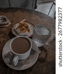 
A simple menu served on a worn dining table in a coffee shop located on the outskirts of the small town of Tembilahan. A cup of coffee with milk, accompanied by grilled pao with a savoury spread