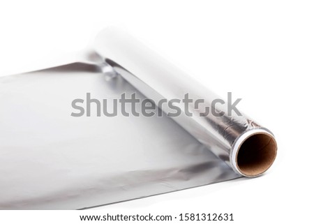 Simple one single roll of shiny silver metal aluminium kitchen foil, tinfoil rolled out, tin foil unrolled isolated on white, surface shown, closeup. Basic kitchen equipment studio shot concept 