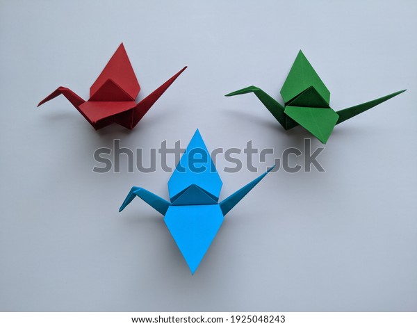 Simple origami birds with three different\
colors and white\
background