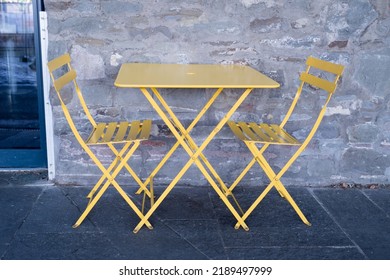 Simple, Painted Yellow Cafe Table And Two Empty Chairs