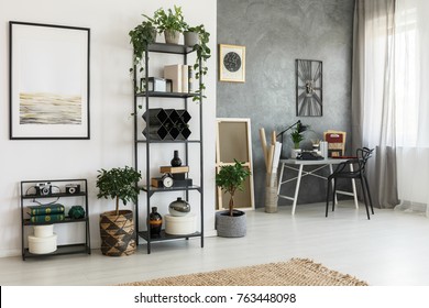 Simple Painting On White Wall In Living Room With Decorations On A Shelf And Plants On The Floor