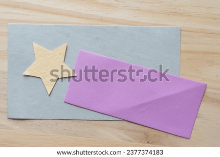 simple paper star and purple paper rectangle on a gray card and wood