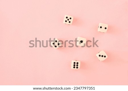 Simple pattern or wallpaper with white and black gaming board game dice on bright pink background. Flat lay view.