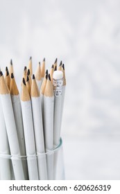 Simple pencils stand in glass light background  one pencil is turned upside down and an elastic band