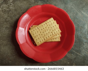 Simple photo of rectangular crackers placed on a red plate over gray background.