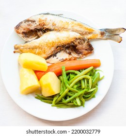 Simple Portuguese Dish Of Whole Grilled Fish (sea Bream) With Boiled Potatoes And Steamed Vegetables (string Green Beans And Carrots). White Plate, Beige Background.