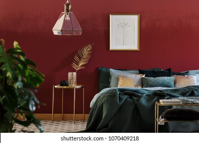 Simple poster hanging above bed with many cushions and green blanket standing in bedroom interior with golden furniture - Shutterstock ID 1070409218