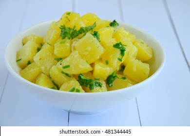 Simple potato salad in a bowl with mustard olive oil dressing garnish with chopped chives and parsley. Selective focus