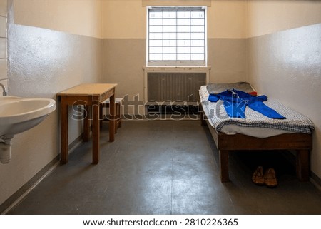 Simple preserved prison cell with bed, sink and table inside the Berlin-Hohenschonhausen Memorial in Berlin, Germany.