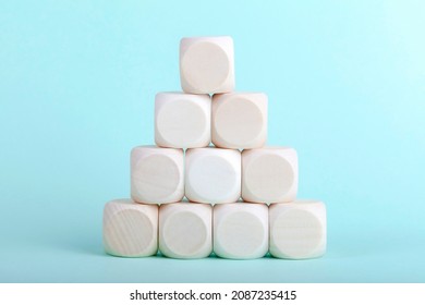 Simple Pyramid Made Of Small Empty Blank Wooden Blocks, Cubes On Light Blue Background. Triangle, Cube Stack Built Structure Object Closeup, Nobody. Business Plan Structural Integrity Abstract Concept