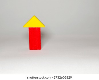 A simple red rectangular block with a yellow triangular arrow on top, symbolizing growth, progress, and rising momentum. Suitable for concepts of development, improvement, and new beginnings in business or education.