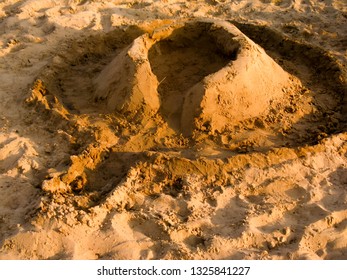 A Simple Sand Wall Made By Children On The Beach. Castle Castle With A Moat To Play On The Sand Near The Water.