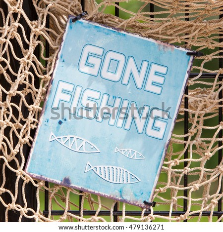 Simple sign on a fishingnet saying gone fishing