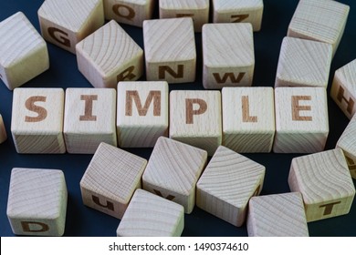 Simple, simplicity make things clear and easy to manage concept, cube wooden block with alphabet combine the word Simple on black chalkboard background.