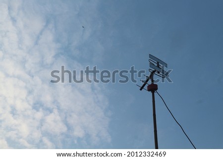 Simple small antenna installed above the house against the background of a clear evening sky.