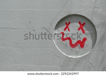 Simple smiling face with crooked mouth spray painted on gray wall recess. Abstract background.