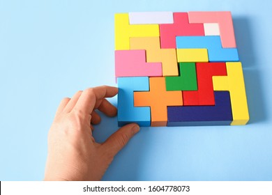 Simple Solutions To Solve Problems. Strategy In Business. Wooden Tetris Cubes In The Hand On A Blue Background As A Puzzle Symbol. The Challenge With A Difficult Solution