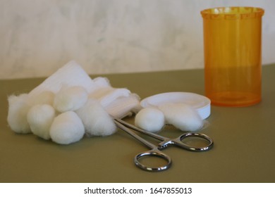 Simple Still Life Of Medical Wound Care Supplies Of Medical Clamp, Gauze, Cotton Balls, And Prescription Medicine Bottle