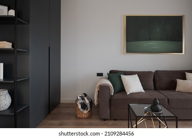 Simple and stylish living room with art, cozy couch, big wardrobe with shelves and decorations